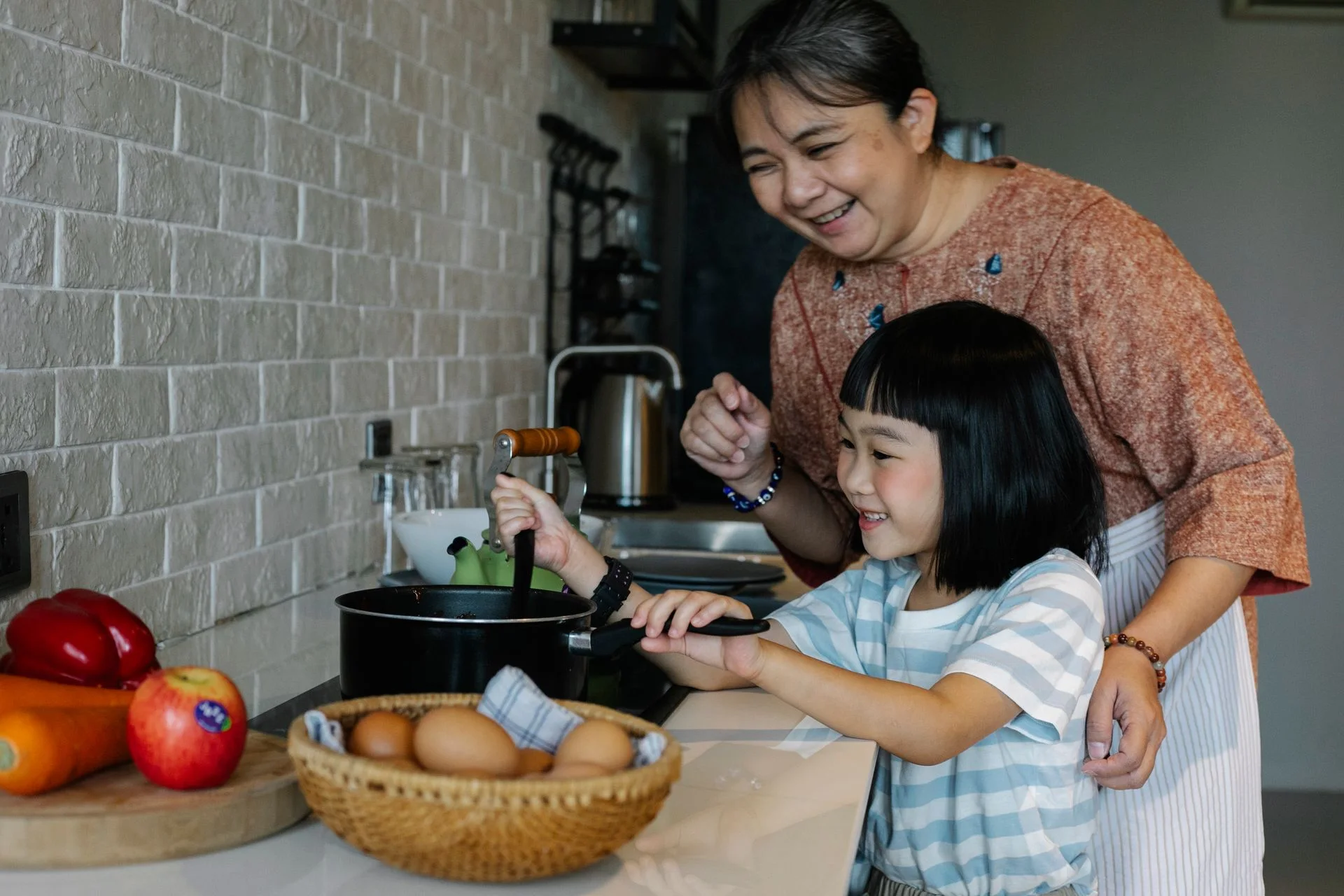 Bà và cháu cùng chuẩn bị bữa ăn trong căn bếp gia đình
